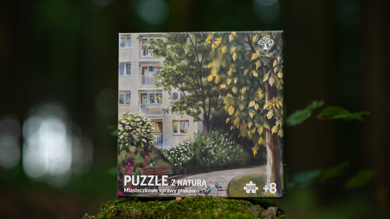 Puzzle z przyrodą, ptakami. Miasto w tle, blok, balkony, suszenie prania, a przed blokiem miejska roślinność, drzewa, krzewy oraz miejskie ptaki - wróble zwyczajne, sroka zwyczajna, jerzyk ,oknówka i gołębie miejskie.