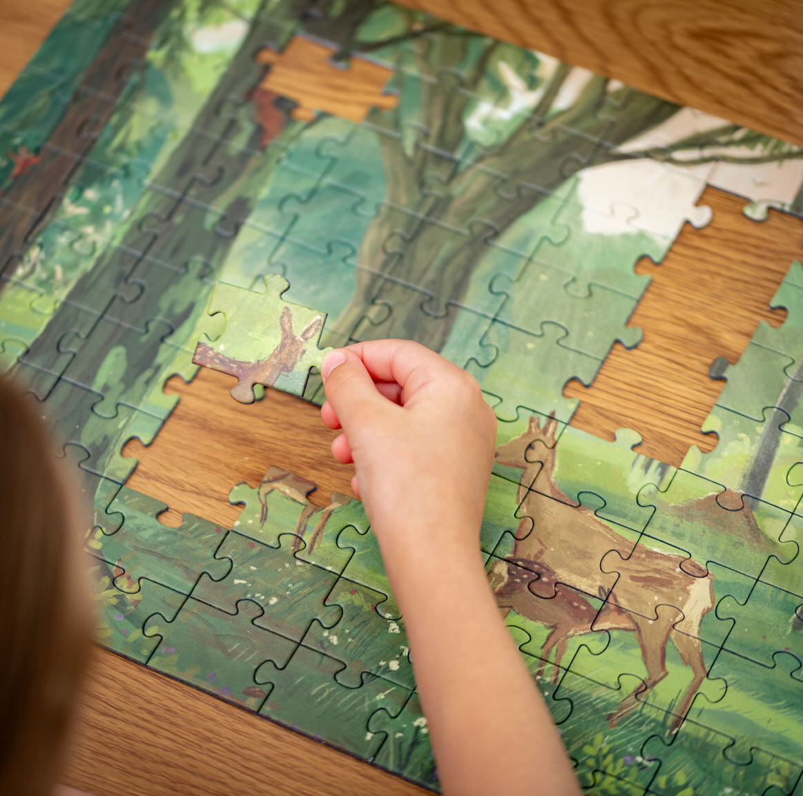 Puzzle dla dzieci i seniorów, puzzle z lasem i sarną europejską. W tle wiosenny las, z kwitnącym czarnym bzem i czarnymi jagodami, kopiec mrówek oraz dzięcioł zielony, wiewiórka pospolita, ryjówka aksamitna. Puzzle przyrodnicze, które warto układać, aby trenować pamięć, spostrzegawczość, koncentrację.