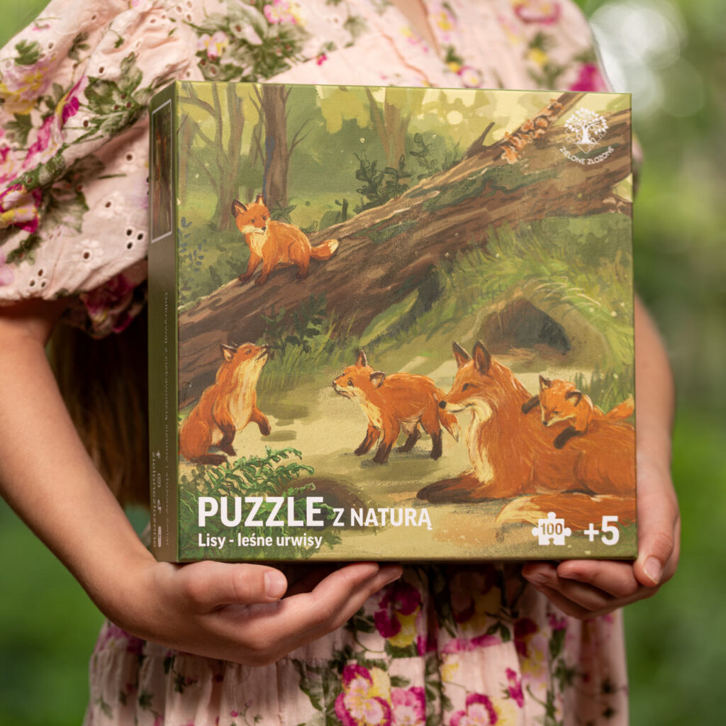 Puzzle z polską przyrodą, do nauki i zabawy, 100 elementowe. Puzzle ilustrowane - scena z lasu z mamą lisicą oraz jej szczeniętami. W tle norka lis&oacute;w, rozkopana gleba, suche gałęzie i powalone drzewa. Młode lisy poznają świat przez obserwację mamy, wsp&oacute;lne zabawy, wspinaczki, gonitwy, zaglądanie w zakamarki.