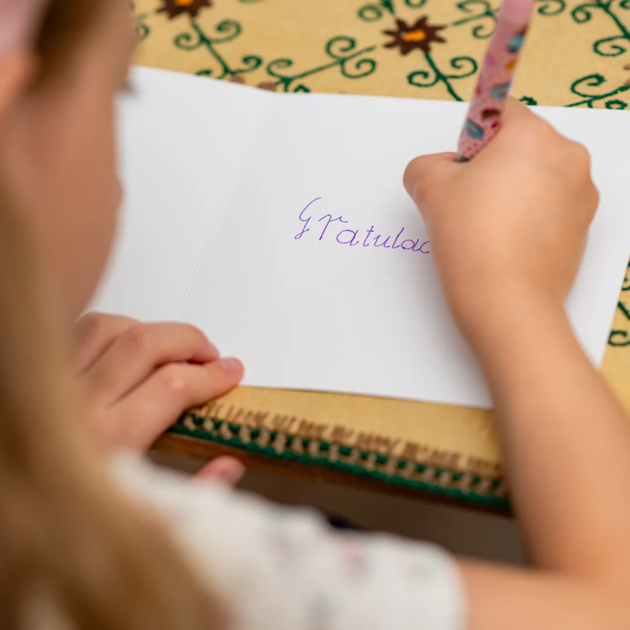 Kartka okolicznościowa z możliwością wpisania osobistej dedykacji, od serca lub wiersza, cytatu o konkretnym znaczeniu. Na zdjęciu wpisywaniem piórem osobistej dedykacji z podziękowaniem i słowem Gratulacje.